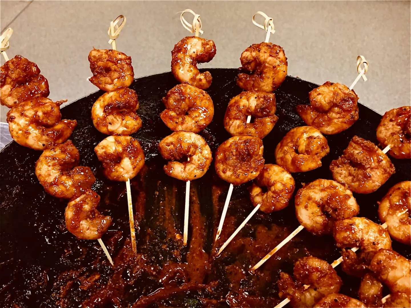 Glazed grilled shrimp skewers on black platter