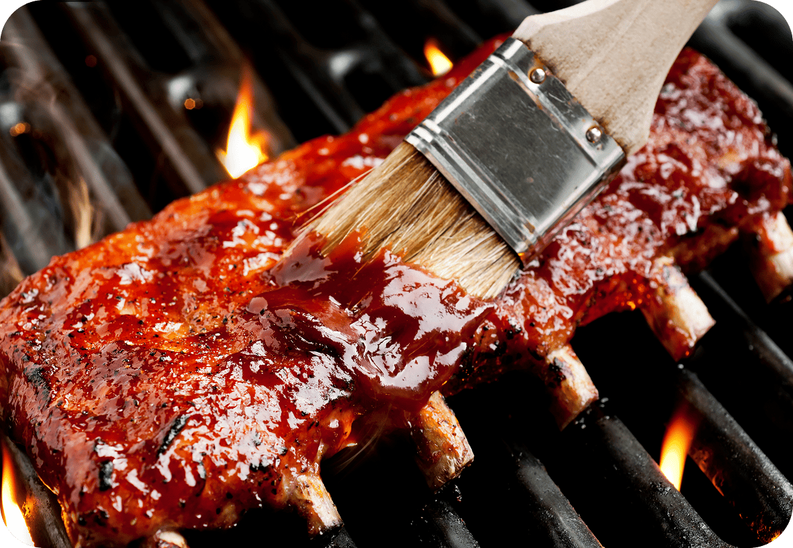 Brushing sauce on grilling ribs