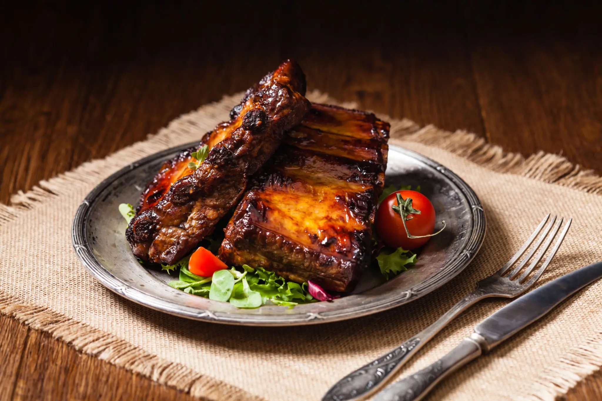 Glazed barbecue pork ribs on plate with salad