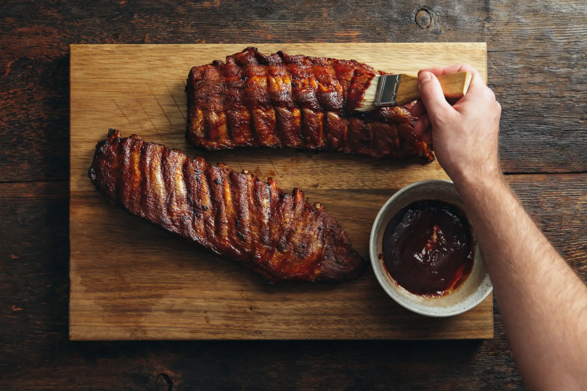 Hand brushing sauce on ribs