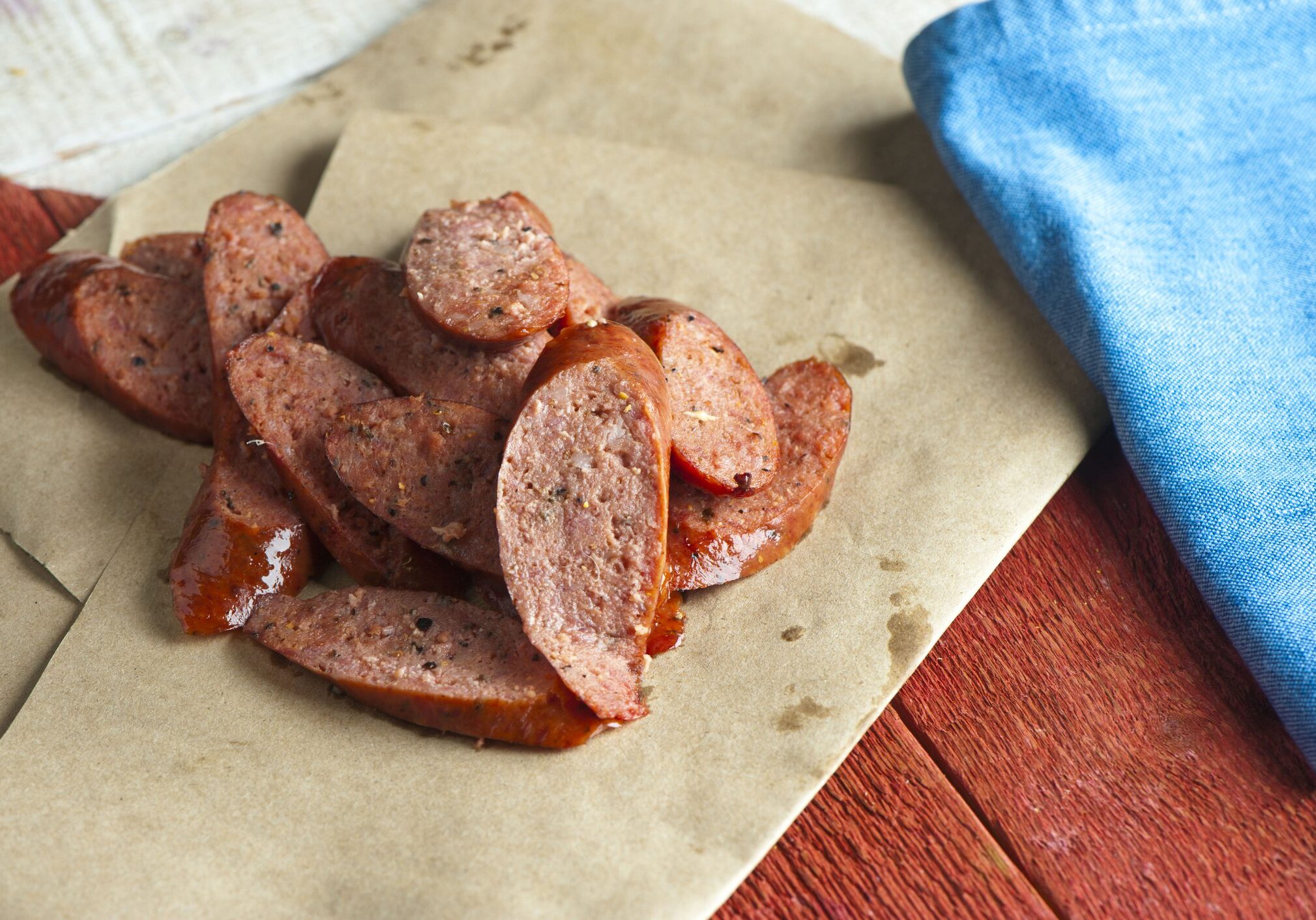 Sliced smoked sausage on brown paper napkin